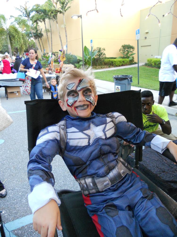 Boy dressed as Captain America sitting in facepainting chair